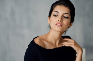 Güzel Lydia. Siyah bir elbise içinde akşam makyajıyla bir sandalyede oturuyor.