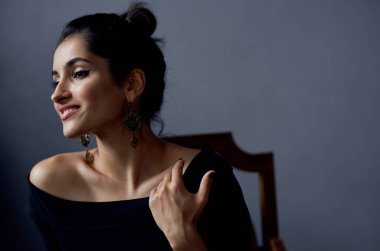 Gri bir odada, sandalyede oturan gece elbisesi içindeki zarif bayan yakın plan çekimleri yaptı.