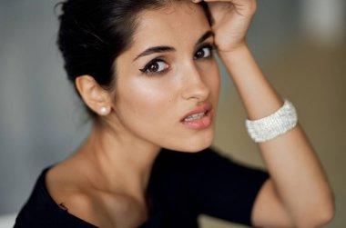 Güzel Lydia. Siyah bir elbise içinde akşam makyajıyla bir sandalyede oturuyor.