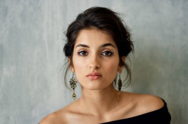 Gece elbisesi giymiş zarif esmer, duvara yaslanmış.