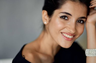 Gri arka planda bileziği olan seksi esmer kadın portresi.