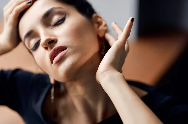 Hermosa mujer con los ojos cerrados toca su cara con sus manos pendientes maquillaje modelo vestido de noche — Foto de Stock