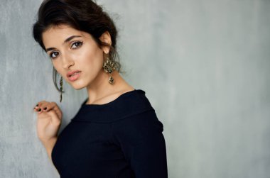 Gece makyajlı seksi bir kadın ve arka planda gri bir portrede küpeli şık bir kadın.