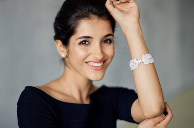 Elinde süslemesi ve gri bir arka planda gece elbisesi olan çekici esmer kadın.