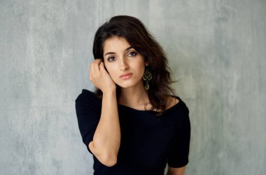 Gece makyajlı seksi bir kadın ve arka planda gri bir portrede küpeli şık bir kadın.