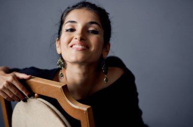  Siyah elbiseli kadın, gri arka planda el kol hareketi yapıyor. 