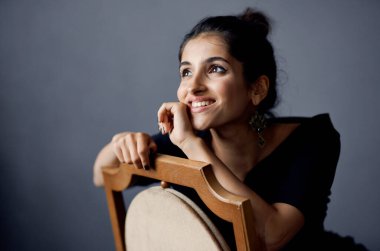  Siyah elbiseli kadın, gri arka planda el kol hareketi yapıyor. 