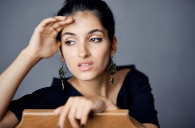 Siyah elbiseli, gri arka planda el kol hareketi yapan seksi kadın yakın plan görüntüsü.