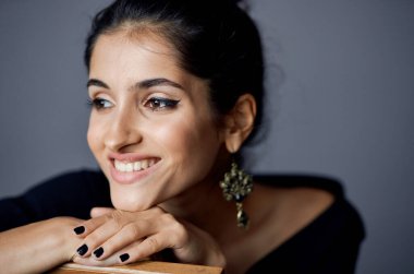  Siyah elbiseli kadın, gri arka planda el kol hareketi yapıyor. 