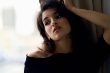 Gece elbisesi giymiş hoş bir bayan pencerenin yanında duruyor ve makyaj modeli.