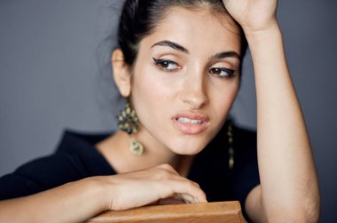 Siyah elbiseli, gri arka planda el kol hareketi yapan seksi kadın yakın plan görüntüsü.