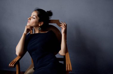 Elbiseli çekici bir kadın sandalyede oturuyor.