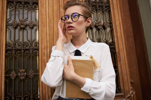 Studentka s brýlemi s knihou v rukou u vysokých dveří vzdělávacího ústavu — Stock fotografie