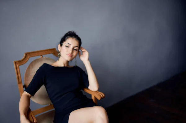 Κομψή κυρία που κάθεται σε μια καρέκλα σε εσωτερικούς χώρους φόρεμα βράδυ hairstyle μοντέλο μακιγιάζ — Φωτογραφία Αρχείου