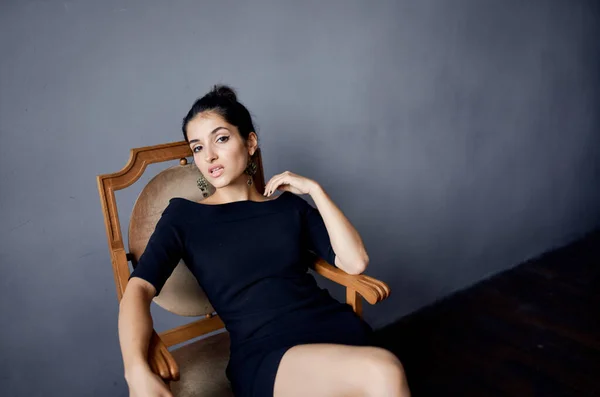 Elegante senhora sentado em uma cadeira dentro de casa vestido de noite penteado maquiagem modelo — Fotografia de Stock