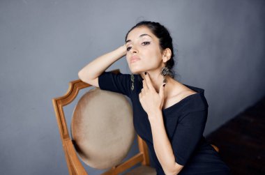 Küpeli seksi bir kadın portresi ve yakın çekimde siyah bir elbise.