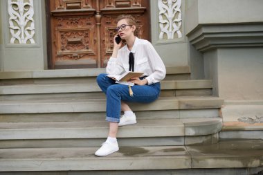 Eğitim enstitüsü yakınlarındaki basamaklar ve gözlükler üzerine kitabı olan bayan öğrenci