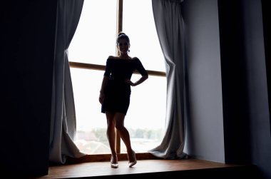 Perde arkasında kısa elbiseli bir bayanın silüeti.