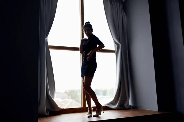 창문 커튼 룸 모델 근처의 짧은 드레스를 입은 여자의 실루엣 — 스톡 사진