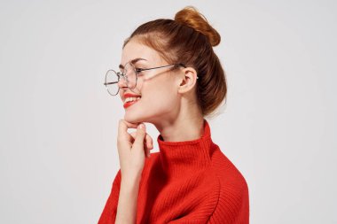 Gözlüklü güzel bir kadının portresi ve kırmızı süveter makyaj lambası arka planı.