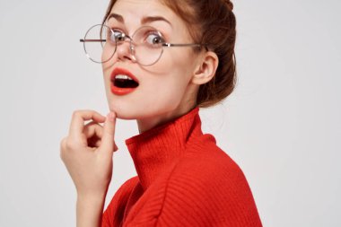 Gözlüklü güzel bir kadının portresi ve kırmızı süveter makyaj lambası arka planı.