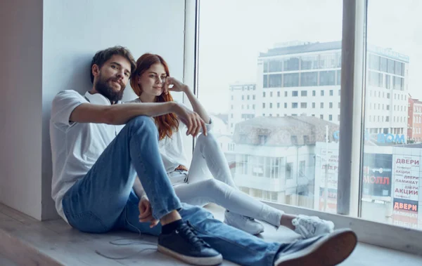 Young couple sitting on the windowsill near the window rest fun lifestyle — Stock Photo, Image