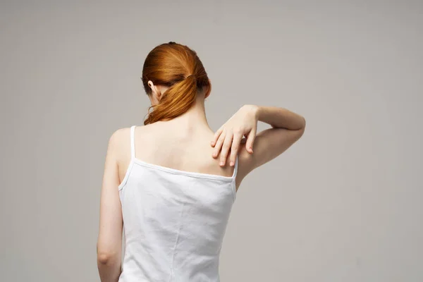 Žena bílá tričko dotýkající se její ramena s rukama oříznutý pohled zblízka — Stock fotografie