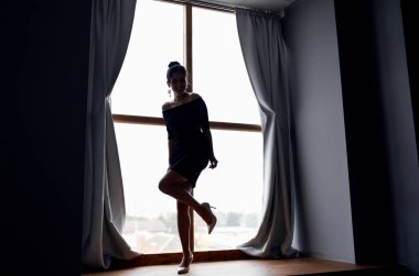 Perde arkasında kısa elbiseli bir bayanın silüeti.