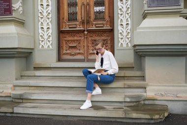 Eğitim enstitüsü yakınlarındaki basamaklar ve gözlükler üzerine kitabı olan bayan öğrenci