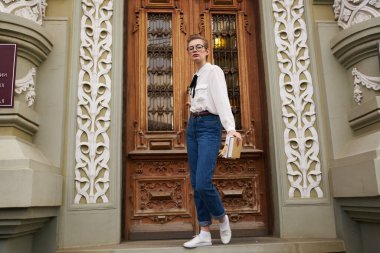 Sokak Eğitim Enstitüsü 'nün kapısının yanında kot giyen bayan öğrenci.