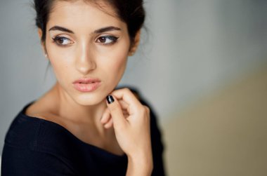 Koyu renk elbiseli zarif bir kadın kapalı mekanda el ele tutuşuyor.