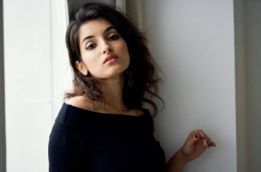 Gece elbisesi giymiş hoş bir bayan pencerenin yanında duruyor ve makyaj modeli.