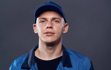 İş üniformalı bir adam mavi şapkalı, manzaralı iş servisini kesmiş.