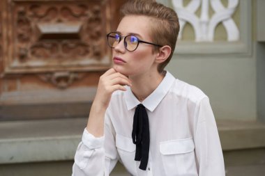 Elinde not defteri olan güzel bir kadın enstitü binasının yakınındaki merdivenlerde oturuyor.