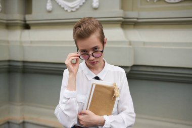 Elinde kitap gözlüğü olan sevimli bir kız öğrenci. Eski moda eğitim enstitüsü.