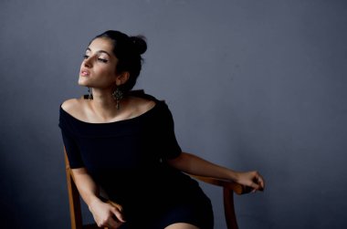 Gri bir odada, sandalyede oturan gece elbisesi içindeki zarif bayan yakın plan çekimleri yaptı.