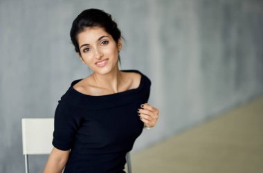 Elinde süslemesi ve gri bir arka planda gece elbisesi olan çekici esmer kadın.