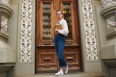 Sokak Eğitim Enstitüsü 'nün kapısının yanında kot giyen bayan öğrenci.