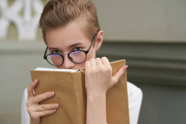 本を手に眼鏡をかけた女子学生が研究所の建物の近くで — ストック写真