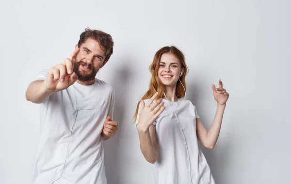 Amigos felices en auriculares escuchan música y bailan sobre un fondo claro — Foto de Stock