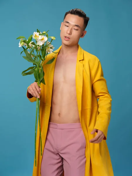 黄色のコートとピンクのズボンの男は白い花の花束を持っています — ストック写真