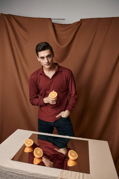 Sliced oranges on the table and reflective mirror man fabric background — Stock Photo, Image