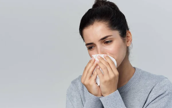 Vrouw blaast haar neus in een servet runny neus gezondheidsproblemen grijs achtergrond — Stockfoto