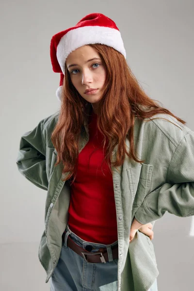 Дівчина в різдвяному капелюсі тримає руки на поясі на сірому фоні — стокове фото