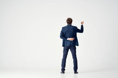 Mavi takım elbiseli bir beyefendi, arka planda hafif bir bakış açısıyla el kol hareketi yapar. Finans sektörü.