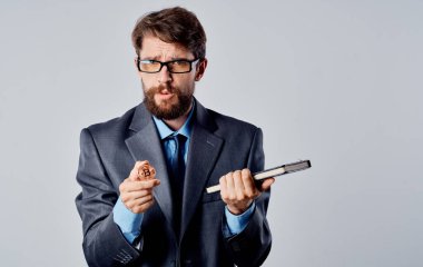 Elinde not defteri olan bir iş adamı gri bir arka plan ve Bitcoin kripto para.