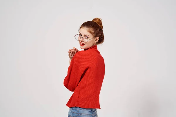 Mulher em uma camisola vermelha e jeans em um fundo leve óculos de penteado modelo emoção — Fotografia de Stock