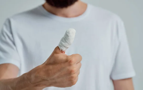 Чоловік у білій футболці перев'язаний великий палець проблеми зі здоров'ям медицина — стокове фото