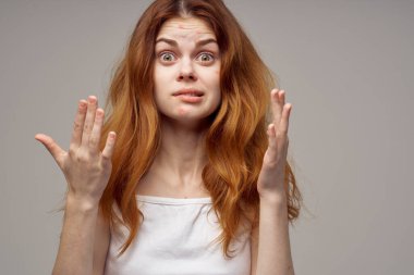 Yüzünde sivilce olan gevşek saçlı bir kadın elleriyle hareket ediyor.