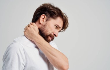 Omurga ağrısı olan boynuna dokunan genç adam. Yan görünüm portresi.